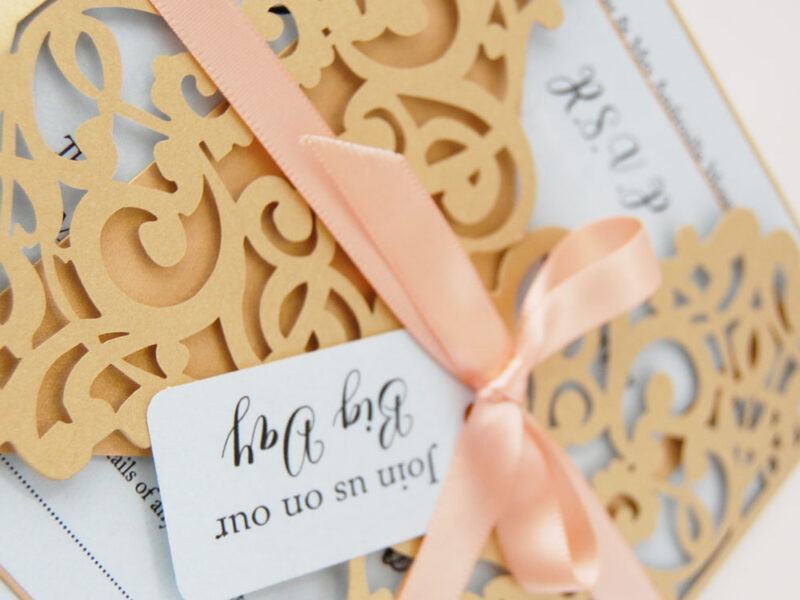 close up of laser cut wedding invitiation suite with ribbon and tag, gate, complete with RSVP card