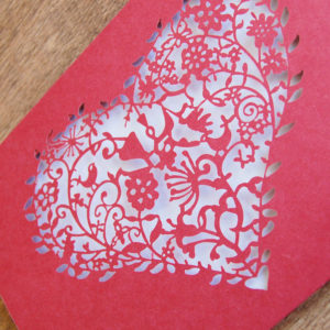 red laser cut wedding invitation with pretty floral heart detail close up